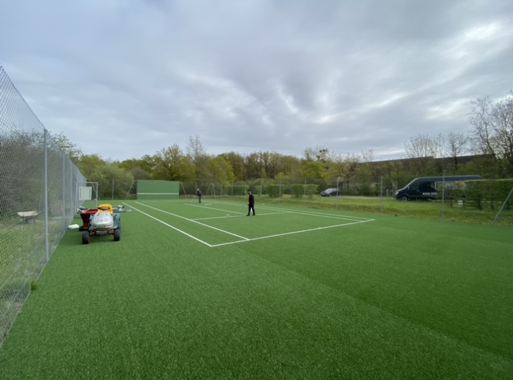 Construction d’un court de tennis en gazon synthétique par ADN-SOL, offrant une surface douce et durable, idéale pour les joueurs de tous niveaux.