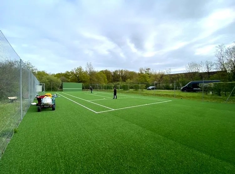 Terrain de tennis en gazon artificiel conçu par ADN-SOL, constructeur de courts de tennis durables.