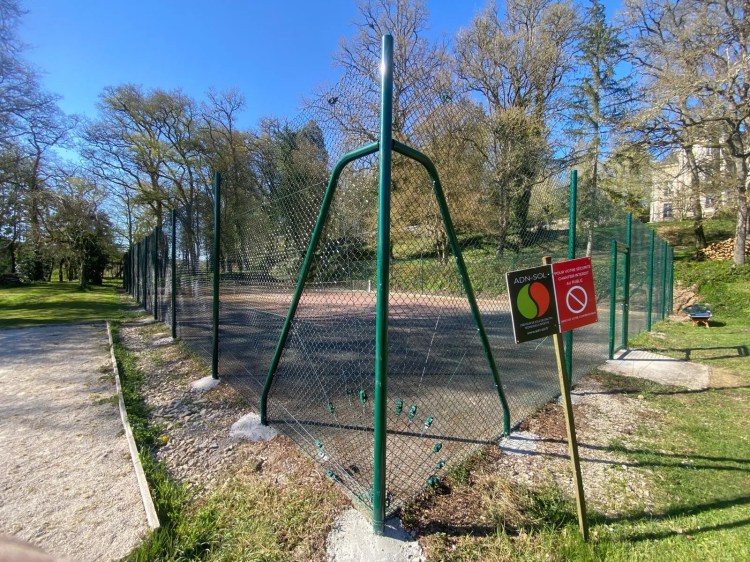 Clôture grillagée verte installée autour d’un court de tennis en plein air, réalisée par l’entreprise ADN-SOL.