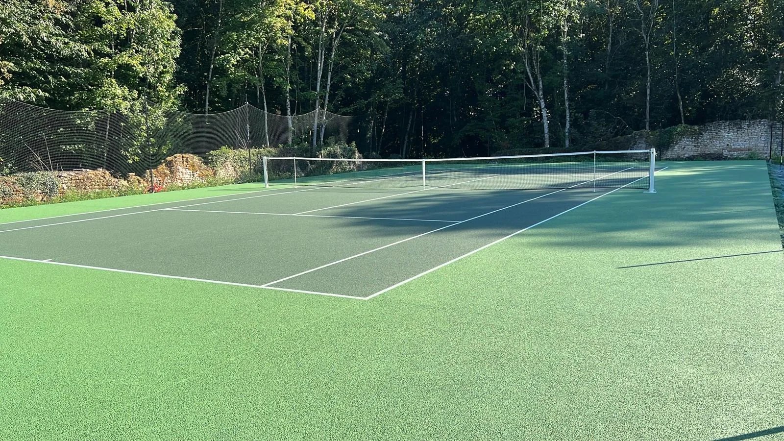 Construction terrain de tennis en béton poreux avec finition teintée verte