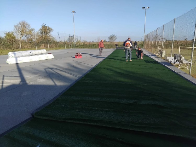 alt="Construction d’un court de tennis en gazon synthétique sur béton poreux avec préparation et pose par ADN SOL"