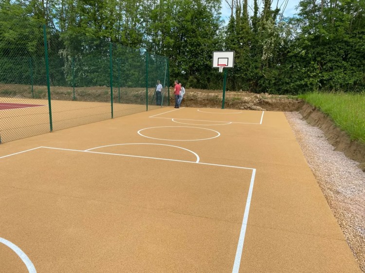 Court de tennis multi-sport en béton poreux avec panier de basket et tracés blancs - réalisation ADN-SOL